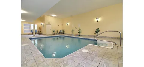 Indoor swimming pool with tiled decking and wall lights.
