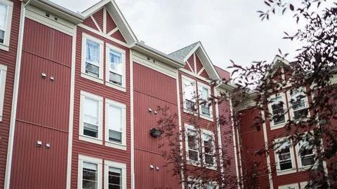 Red and cream building façade with gabled roofs, windows and trees.