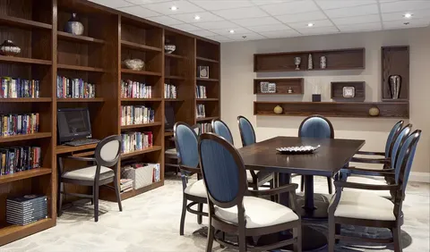 Library with bookshelves, a computer and a table with chairs