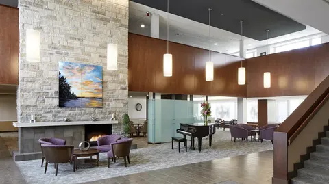 Room with purple armchairs, a fireplace and a grand piano