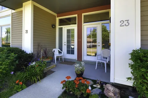 Covered porch with doors, white chairs and flower pots