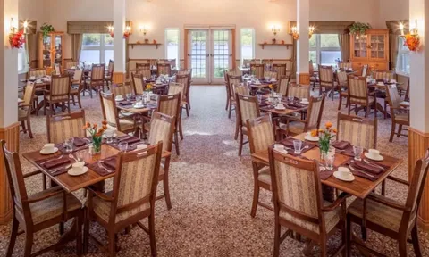Dining room with set tables, wooden chairs and doors overlooking the water