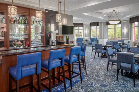 Bar with blue chairs, pendant lights and nearby tables