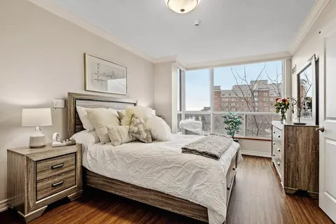 Bedroom with a made bed, bedside tables and a dresser beside a window