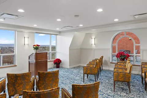 Room with rows of upholstered chairs and a wooden lectern