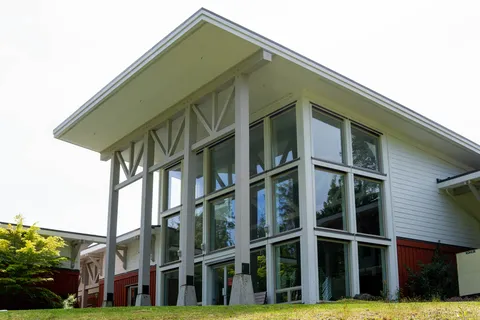 Windowed residence wing with a sloped roof and a lawn.