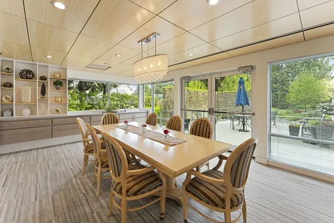 Room with a long wooden table, striped chairs, display shelves and patio doors
