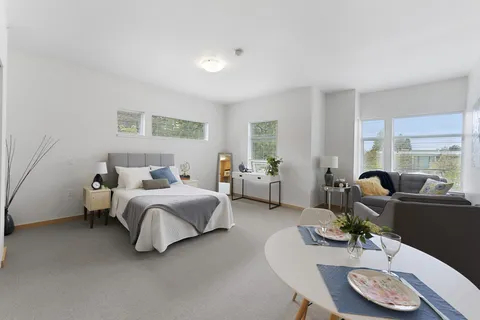 Room with a double bed, sofa, armchair, round dining table and several windows