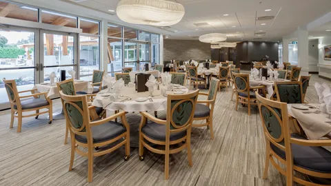 Dining room with round set tables, upholstered wooden chairs, pendant lights and patio windows