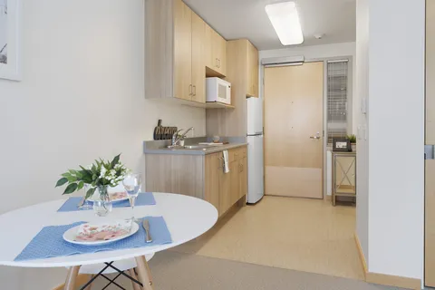 Kitchenette with wooden cabinets, a sink, microwave, refrigerator and a round table