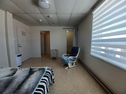 Bedroom with a rocking recliner, striped window blind and a mirrored closet