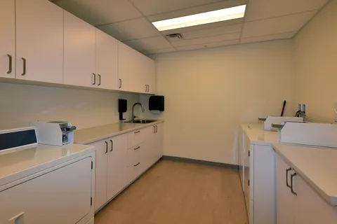 Laundry room with washers, dryers and white cupboards.