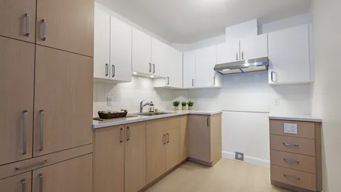 Suite kitchen with white cabinets and a wooden pantry.
