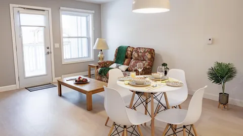 Suite sitting and dining area beside tall windows.