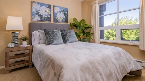 Suite bedroom with a bed, bedside tables and a large window.