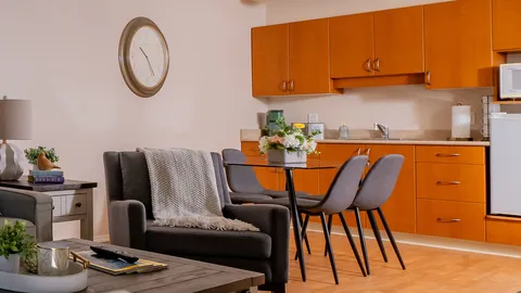 Suite living area and kitchenette with wooden cabinets.