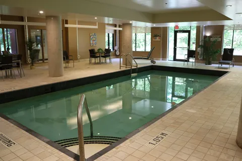 Indoor swimming pool with surrounding seating and windows.