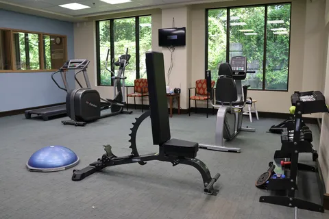 Fitness room with exercise machines, a weight bench and dumbbells.