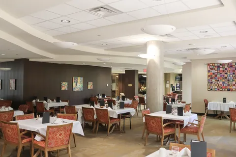 Dining room with white table linens and red upholstered chairs.