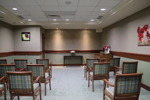 Chapel with rows of chairs facing a cross and table.