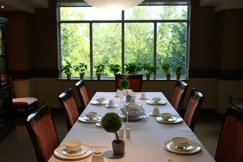 Private dining room with a long table beside a large window.