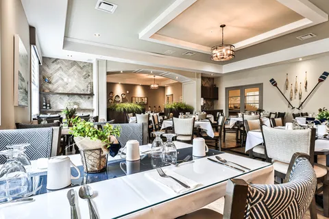 Dining room with set tables, upholstered chairs and ceiling lights.