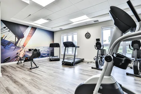 Fitness room with treadmills, exercise machines and a sailing mural.