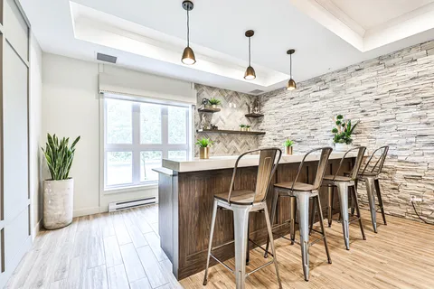 Room with a counter, high stools and stone accent wall.