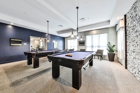 Games room with two billiards tables and windows.