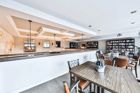 Library lounge with tables, chairs and shelves of books.