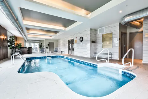 Indoor pool with entry rails and seating around the water.