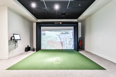 Indoor golf simulator with a hitting mat and projection screen.