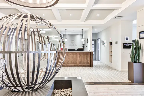 Reception lobby with a wooden desk and a metal globe sculpture.