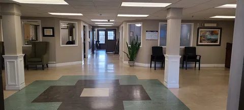 Lobby with patterned flooring, white columns, armchairs and a potted plant
