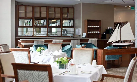 Set dining tables beside a wooden cabinet and a model sailboat