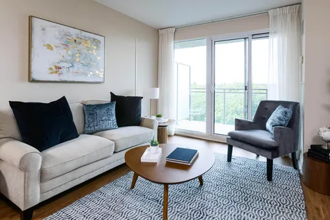 Sofa and armchair around a round coffee table beside balcony doors