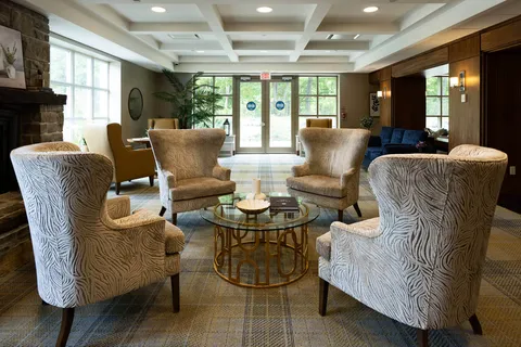 Armchairs around a glass coffee table beside a stone fireplace and glass entrance doors