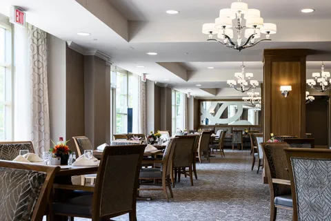 Dining room with set tables, upholstered chairs, chandeliers and large windows