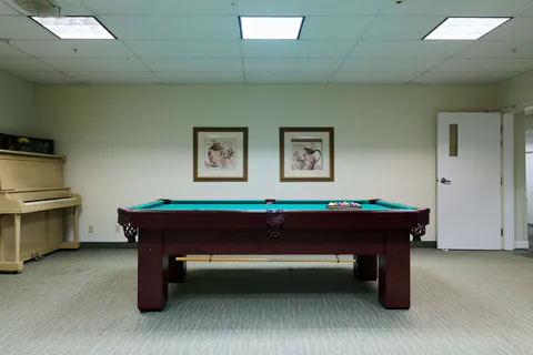 Billiards room with a pool table, upright piano and framed pictures of jugs
