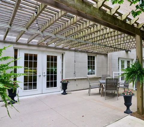 Patio with a table, chairs and planters beneath a pergola