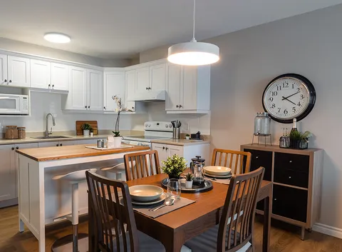 Kitchen and dining area with white cabinets, a wooden table and four chairs