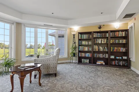 Library seating beside bookshelves and large windows.
