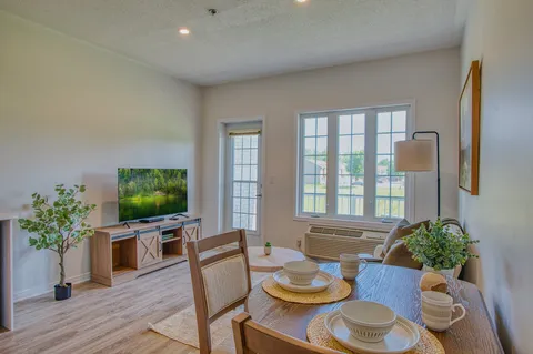 Suite dining and living area with a table, armchairs and television.