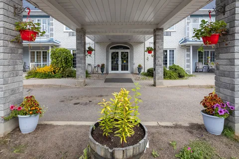 Covered entrance with stone columns, flower baskets and planters.