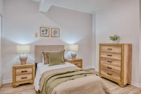 Bedroom with a bed, wooden nightstands and dresser.