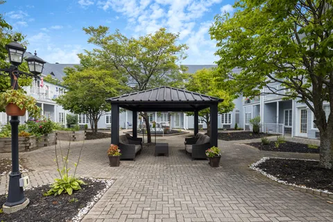 Courtyard gazebo beside garden beds, trees and paved paths.