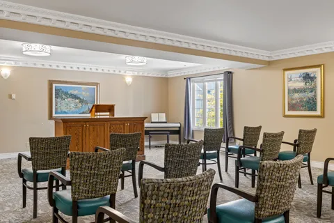 Chairs facing a piano in a room with glass doors and wall artwork.