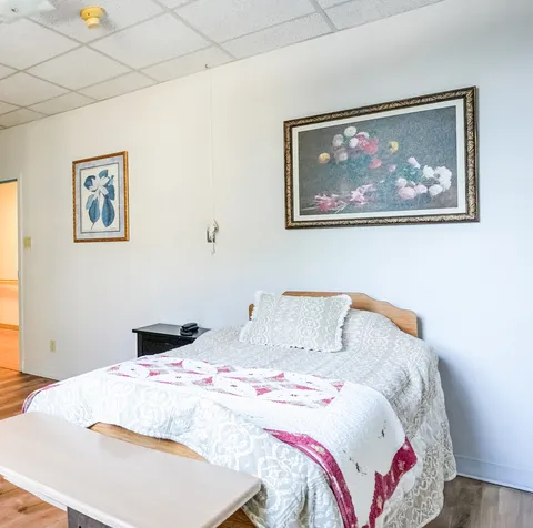 Bedroom with a bed, side table and framed floral artwork