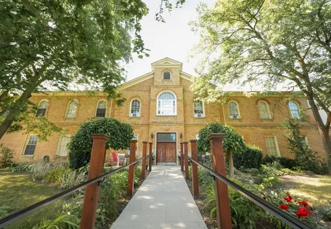 Two-storey yellow-brick residence with arched windows and a ramp leading to wooden doors