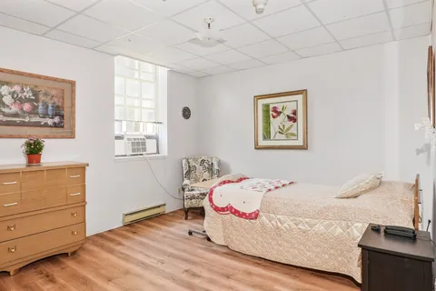 Bedroom with a bed, dresser, armchair and framed floral artwork
